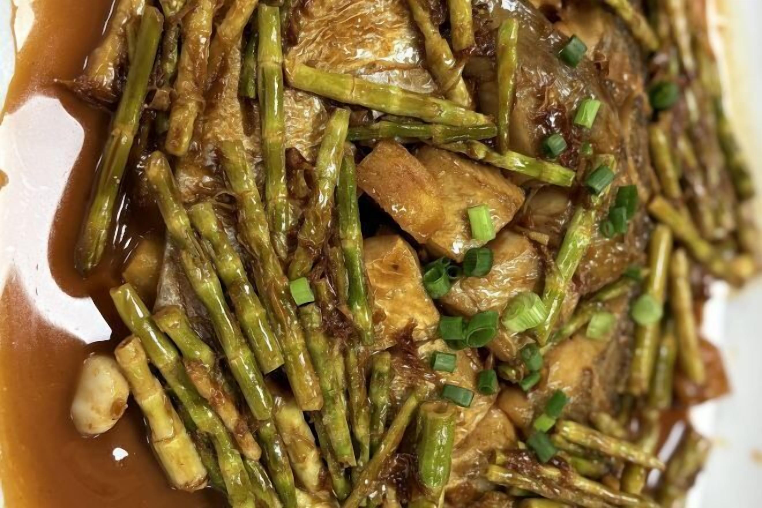 A close-up of a stir-fried dish with vegetables and meat, garnished with chopped green onions.