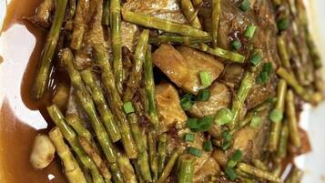 A close-up of a stir-fried dish with vegetables and meat, garnished with chopped green onions.