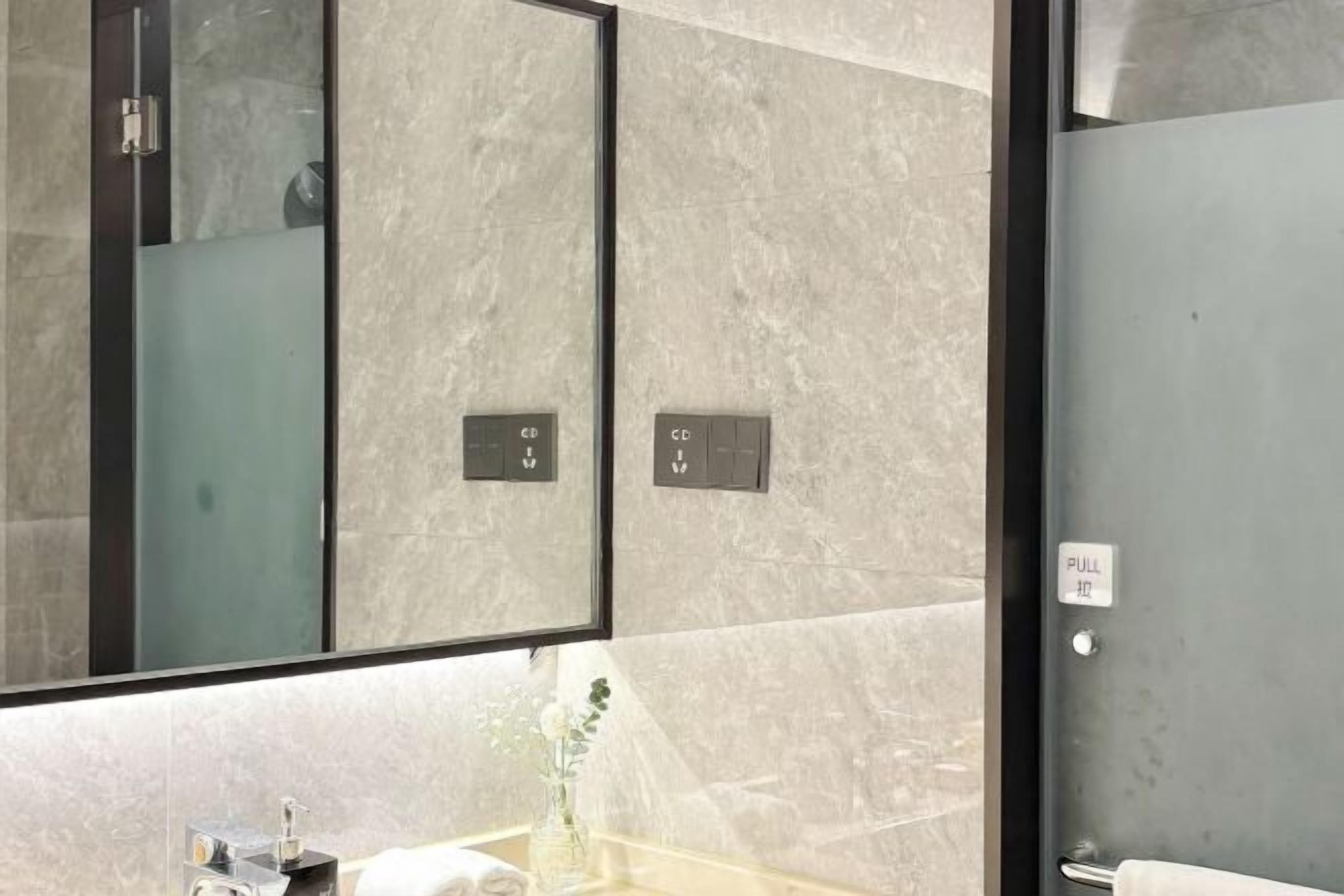 A modern bathroom with a large mirror, two towel racks, and a glass shower enclosure.
