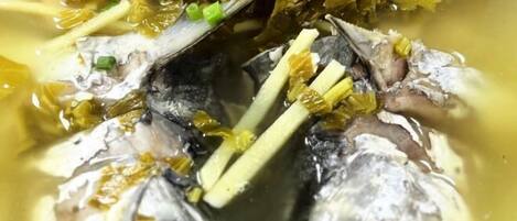 Primer plano de un plato de pescado con cebollas verdes y algas.