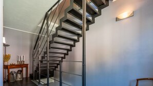 A modern spiral staircase with metal railings and a wooden console table with candles and decorative items.