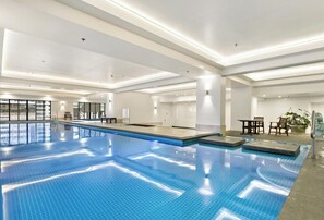 An indoor swimming pool with clear blue water, surrounded by white walls and ceiling.