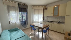 A compact kitchen with a dining table, chairs, and a kitchenette. - Lovely apartment for 4 people with A/C, TV and pets allowed (Rosolina)