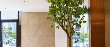 A modern lobby with a large window, a seating area, and a tree.