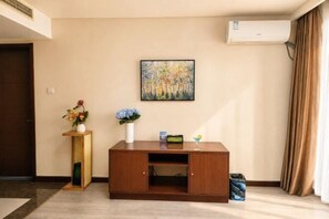A room with a wooden cabinet, a painting, and a vase with flowers.