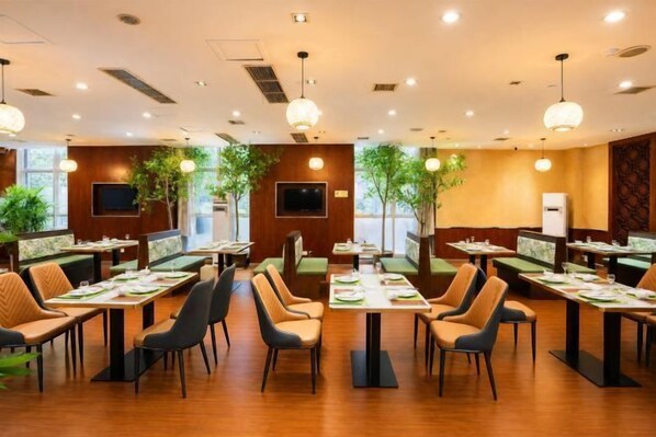 Un restaurante con varias mesas y cabinas, luces de techo y plantas en macetas.
