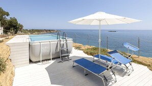 Ett poolområde med en bubbelpool, solstolar och ett parasoll.