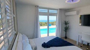 Une chambre avec un grand lit, une télévision et une vue sur une piscine.