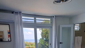 Une chambre dotée d’un grand lit, offrant une vue sur une piscine et donnant accès à un balcon par une porte.