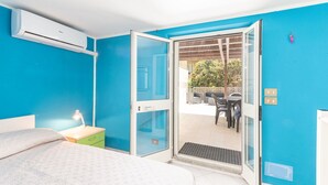 A bedroom with a bed, a nightstand, a lamp, and a sliding glass door leading to an outdoor patio with a table and chairs. - Stunning private villa for 5 guests with WIFI, A/C, TV, patio and pets allowed (Castiglione Della Pescaia)
