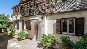 A two-story building with a balcony, potted plants, and a window with shutters. - Stunning private villa for 5 guests with WIFI, A/C, TV, patio and pets allowed (Castiglione Della Pescaia)