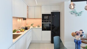A modern kitchen with white cabinets, a black refrigerator, and a glass dining table. - Cosy apartment for 6 people with WIFI, A/C, TV and patio (Telde)