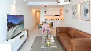 A modern living room with a TV, a glass coffee table, a brown leather sofa, and a dining area with chairs and a pink tablecloth. - Cosy apartment for 6 people with WIFI, A/C, TV and patio (Telde)