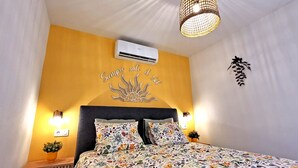 Un dormitorio con una cama, aire acondicionado, un adorno en la pared y dos lámparas de pared.