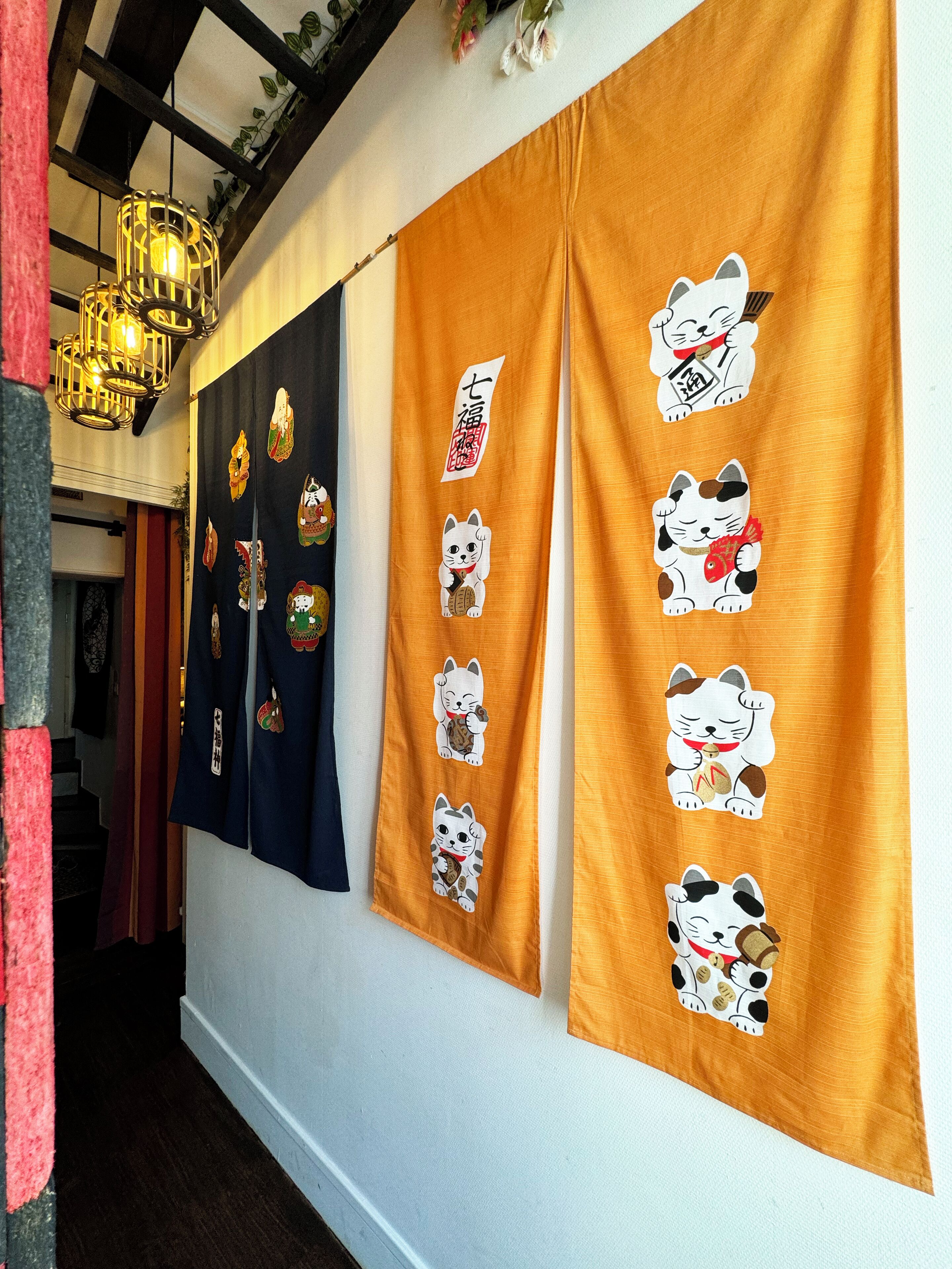 Un pasillo con una fila de cortinas con diseños tradicionales japoneses y una lámpara colgante.