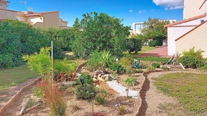 A residential area with a garden, pathway, and buildings with red-tiled roofs. - Nice apartment for 4 guests with WIFI, TV and terrace (Port Leucate)