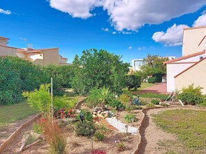 A residential area with a garden, pathway, and buildings with red-tiled roofs.