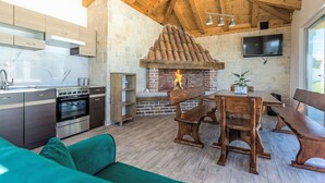 A modern kitchen with a stone wall and a wooden ceiling, a dining area with wooden furniture, and a TV mounted on the wall. - Stunning private villa for 8 guests with A/C, hot tub, WIFI, private pool, TV and terrace (Zadar)