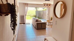 A hallway leading to a living area with a sofa, a table, and a hanging plant. - Maison Moderne Avec Jardin (Saint Xandre)