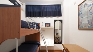 A dormitory room with bunk beds, a desk, a chair, a mirror, and a painting on the wall.