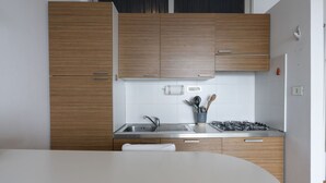 A modern kitchen with wooden cabinets, a stainless steel sink, a gas stove, and a white countertop.
