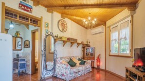 Un salon chaleureux avec un plafond en bois, un canapé à motifs floraux, une horloge et un téléviseur.