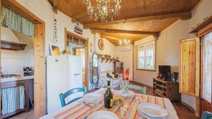 Un intérieur chaleureux en bois, avec une table à manger pour quatre personnes, un coin cuisine équipé d’un réfrigérateur et d’une cuisinière, et un téléviseur placé dans un coin.