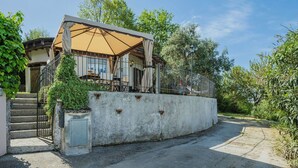 Une maison dotée d’un patio couvert, d’un mur en béton et d’un escalier menant à l’entrée.