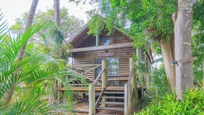 Eine Holzhütte mit der Aufschrift "Possum Lodge", umgeben von üppigem Grün.