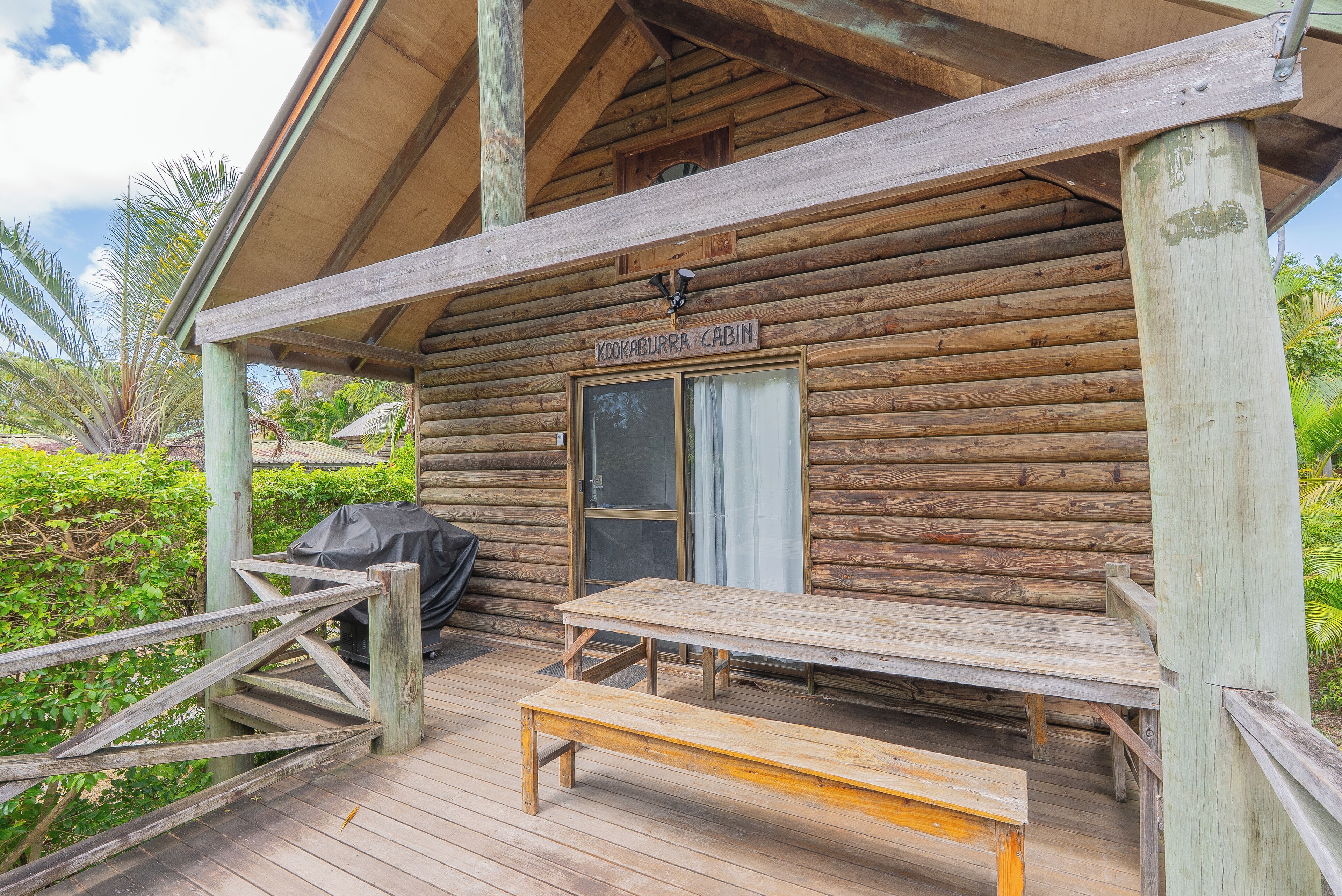 A wooden cabin with a porch, a table, and a bench.