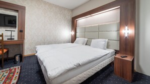 Ein ordentlich eingerichtetes Hotelzimmer mit einem großen Bett, einem Schreibtisch und einem Fernseher.