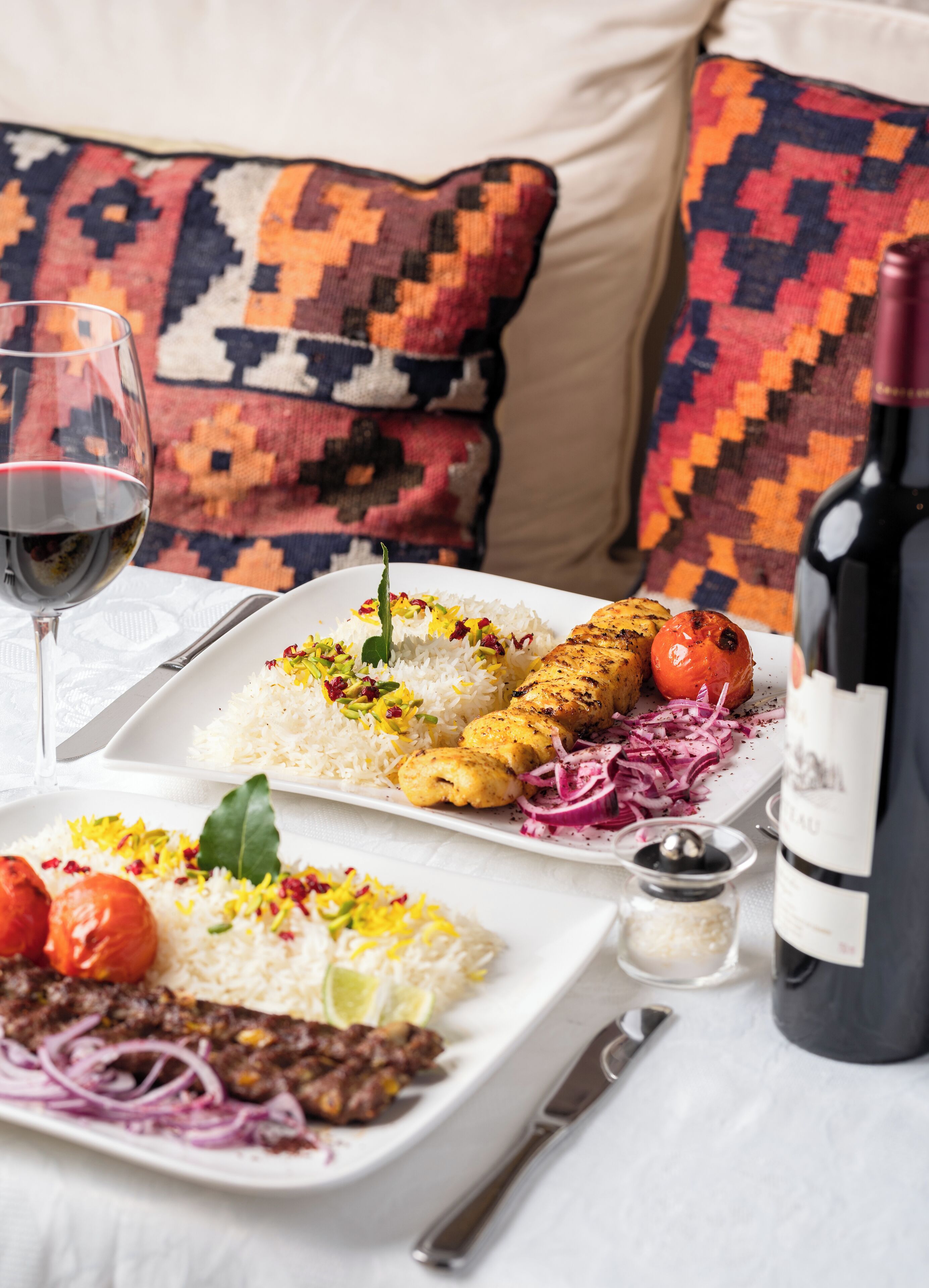 A dining table with a plate of food, a wine bottle, and a glass of wine.