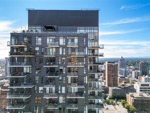 Un edificio de varios pisos con balcones, grandes ventanales y vistas a la ciudad.