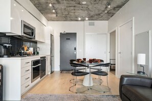 Una cocina moderna con comedor, un sofá de cuero negro y una mesa de vidrio.