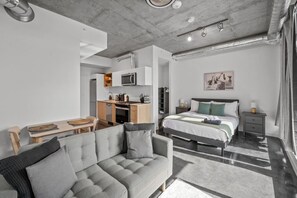 Un dormitorio moderno con cama, mesitas de noche y vistas a la cocina.
