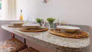 Une table à manger, agrémentée de sets de table, d’assiettes et de couverts, placée devant un comptoir de cuisine.