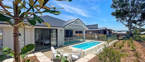 A modern house with a swimming pool, outdoor seating, and a well-maintained garden.