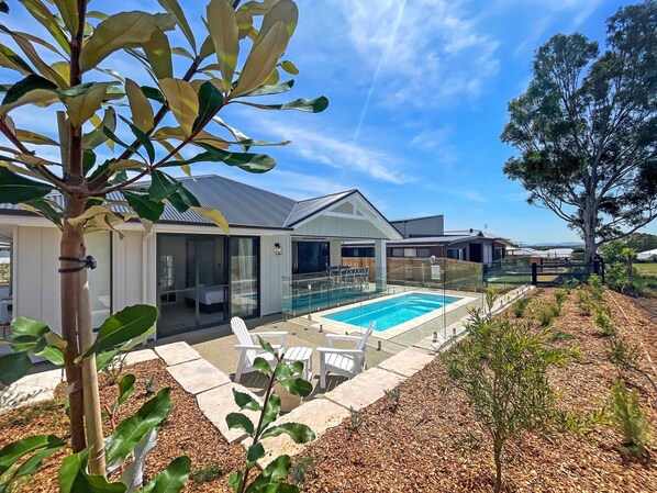 A modern house with a swimming pool, outdoor seating, and a well-maintained garden.