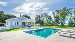 A modern house with a swimming pool, outdoor furniture, and a garden.