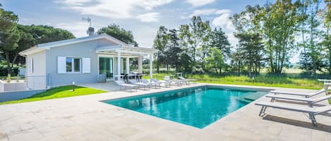 Una casa moderna con piscina, muebles de jardín y un jardín.