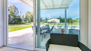 A room with a sliding glass door leading to an outdoor area with a pool and patio furniture.