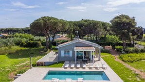 A modern house with a swimming pool, surrounded by lush greenery and trees.