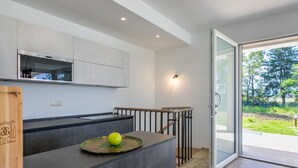 A modern kitchen with a built-in oven, a wooden cutting board, and a green apple on the counter.