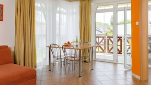 A dining area with a table and chairs, a sofa, and a sliding glass door leading to an outdoor area. - Cosy apartment for 4 guests with A/C, WIFI, TV and terrace (Tapolca)