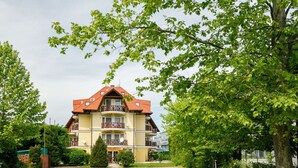 A multi-story building with a red-tiled roof, balconies, and a paved driveway. - Cosy apartment for 4 guests with A/C, WIFI, TV and terrace (Tapolca)