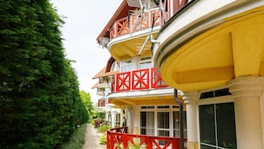 A row of multi-story buildings with balconies, a paved pathway, and a red fence. - Cosy apartment for 4 guests with A/C, WIFI, TV and terrace (Tapolca)