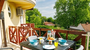 An outdoor dining area with a table set for breakfast, including croissants, juice, and coffee.