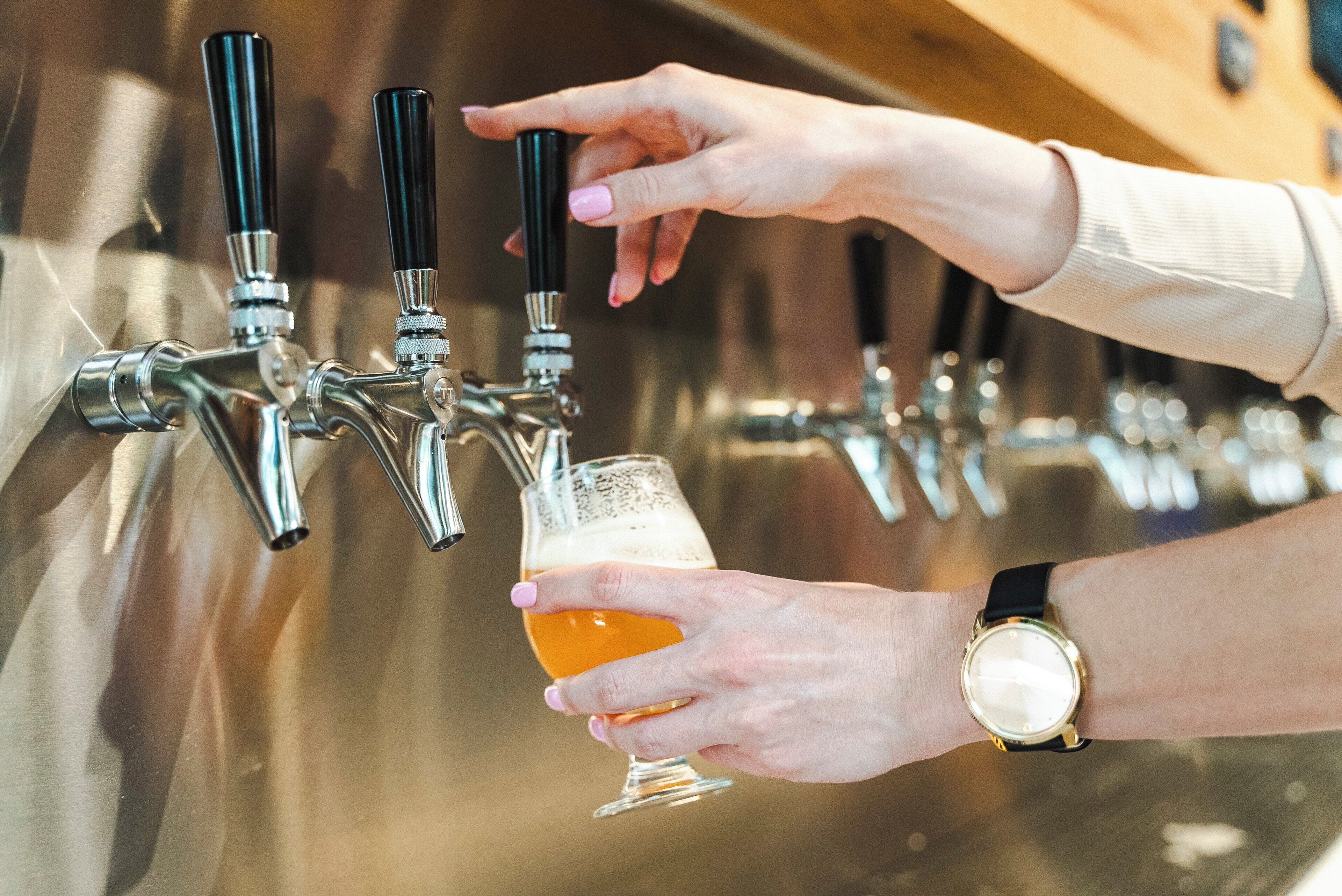 Eine Person zapft Bier in ein Glas.