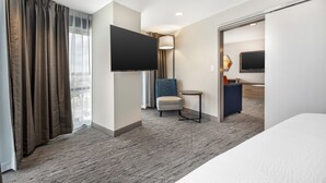 Une chambre d’hôtel avec un grand lit, un téléviseur à écran plat, une petite table ronde, une chaise et un bureau avec une autre chaise.