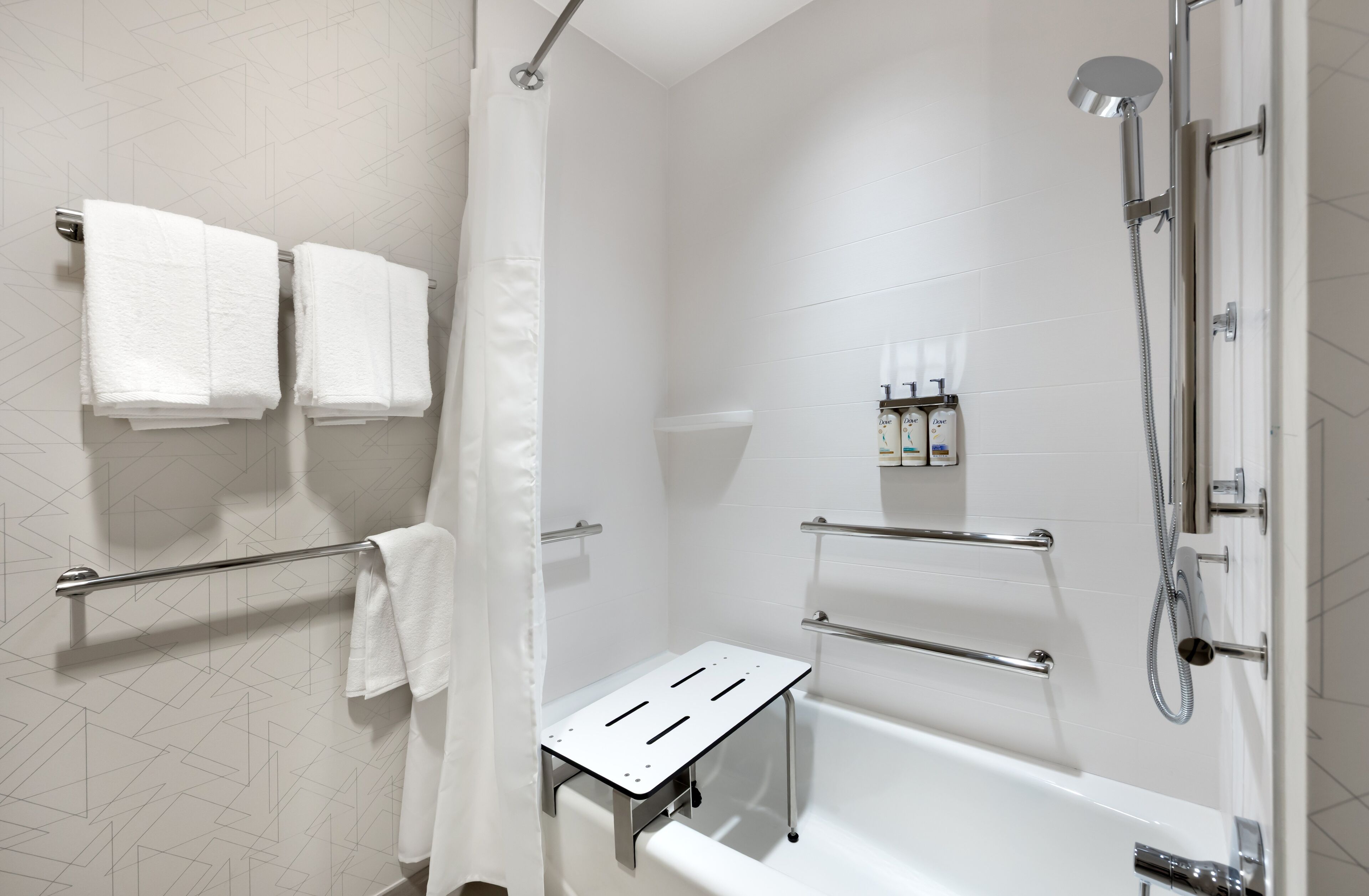 Une salle de bain moderne équipée d’une baignoire, d’une douche et de barres d’appui.